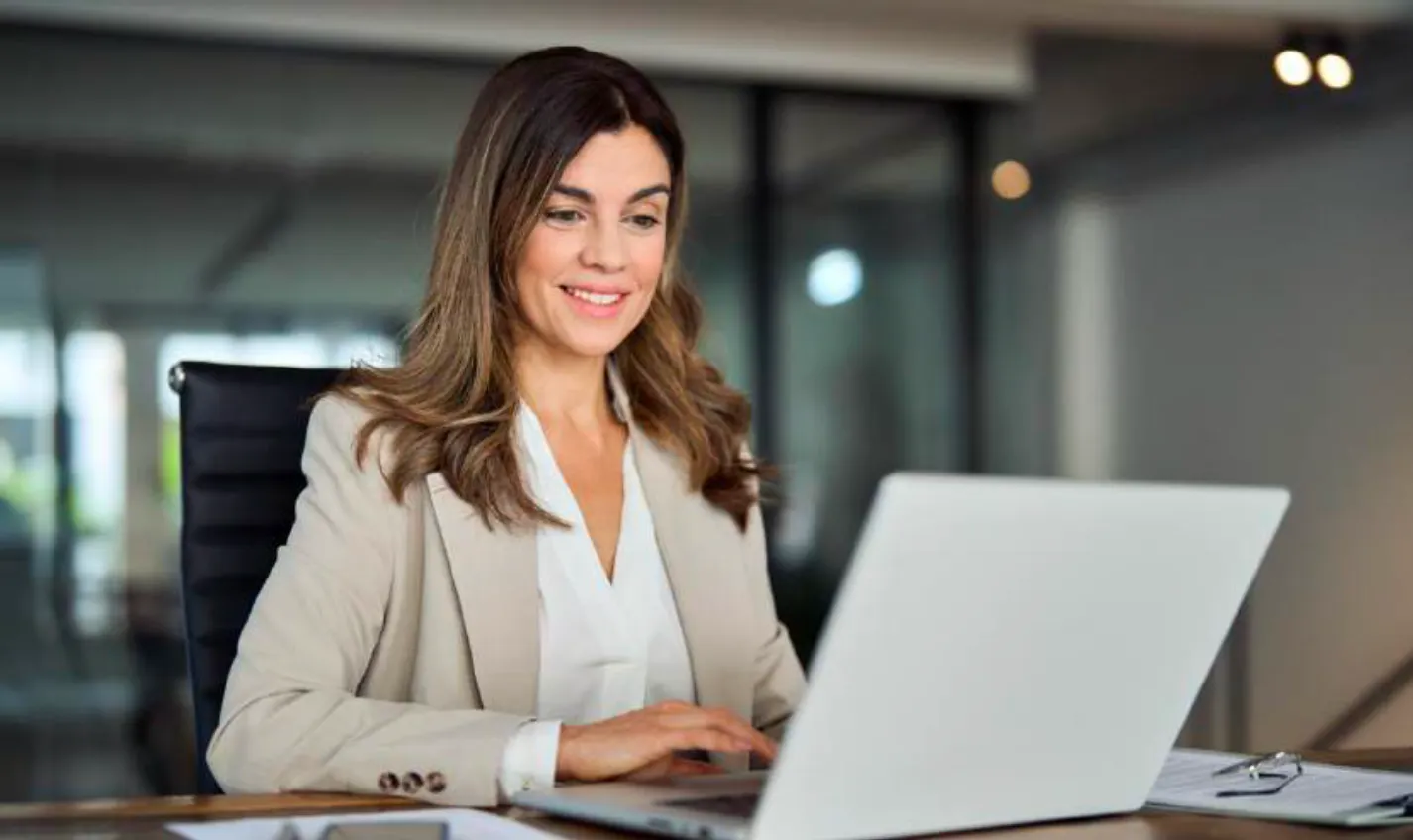 Smiling busy mature middle aged professional business woman working on laptop