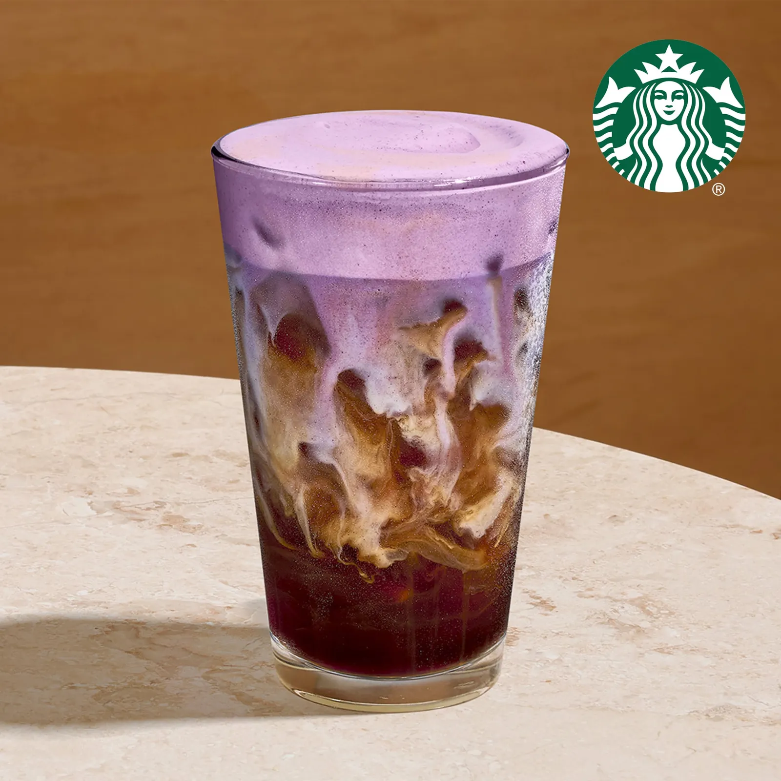 A photograph of an iced coffee drink with cold purple ube foam