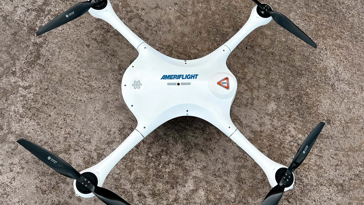 a top view of Ameriflight's M2 drone which sits on the ground, and features a body and four propellers.