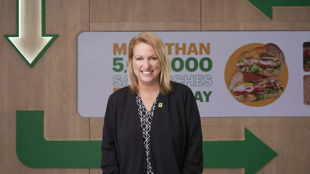 An image of a woman standing in front of a Subway logo.