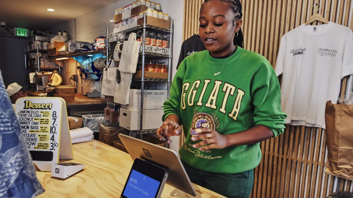 A cashier making an order on a Square kiosk.