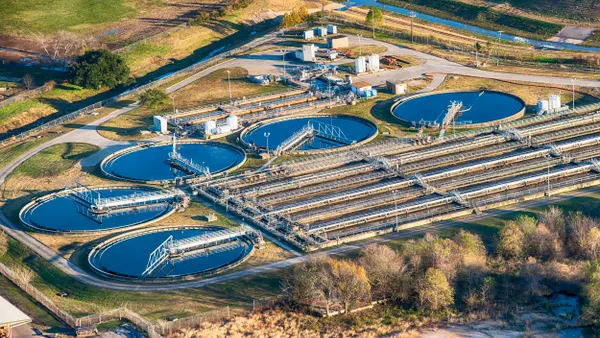 Aerial view of a water treatment plant with 5 large circular pools of blue water and rows of pipes.