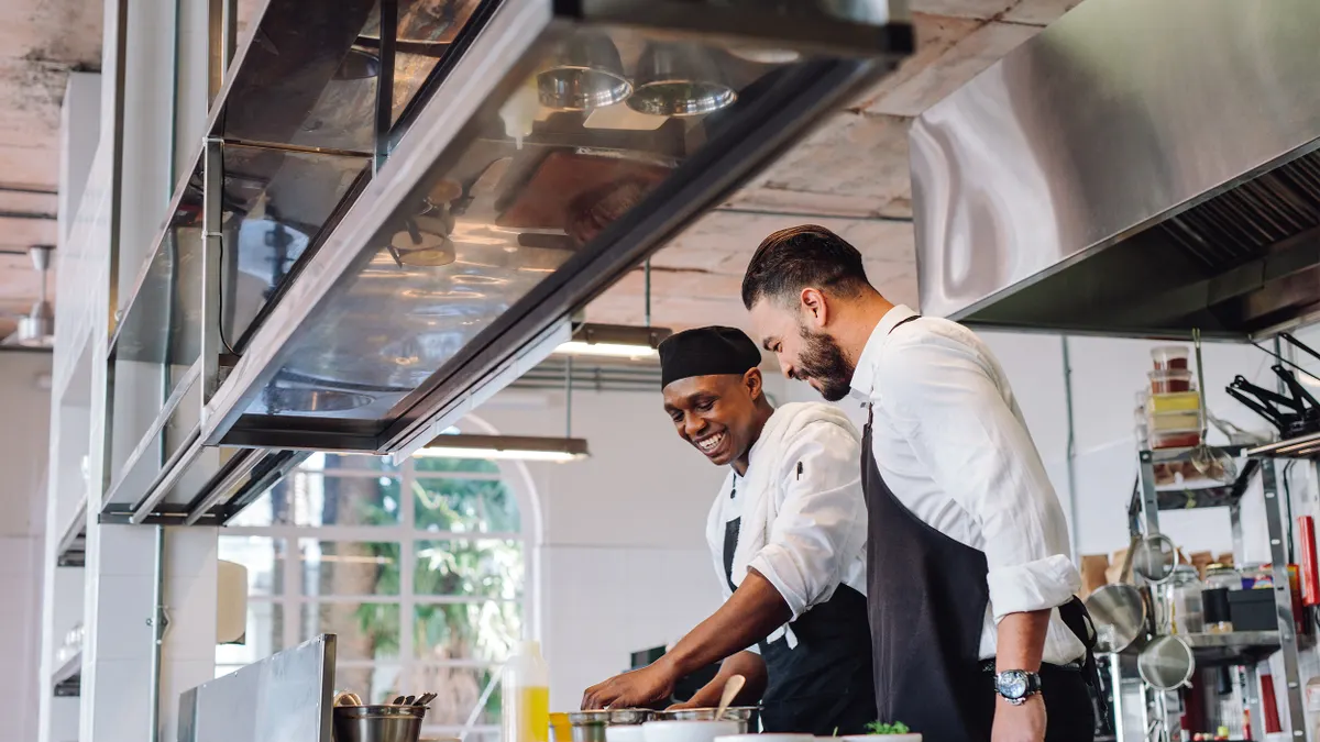 Two cooks preparing food in restaurant kitchen