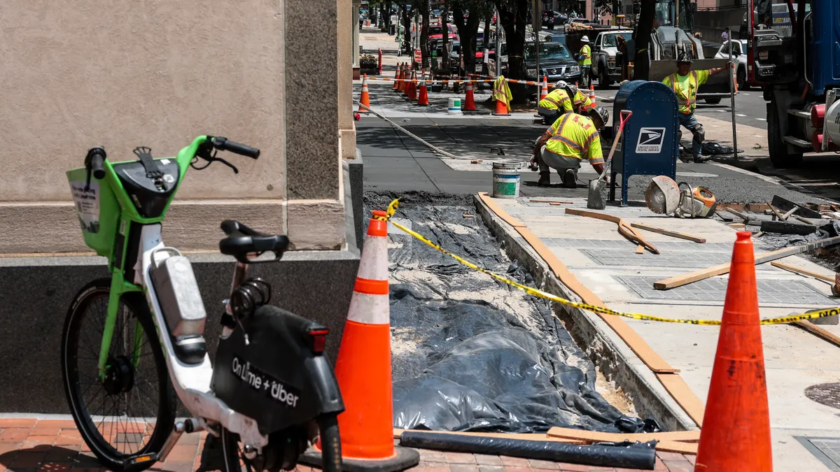 Construction workers lay cement on a sidewalk