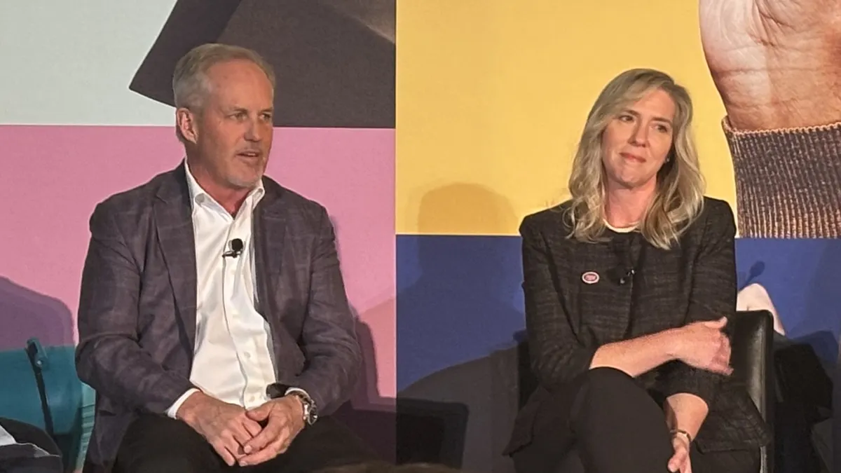 Two people sit on a stage.