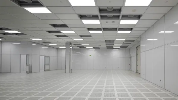 An empty, white room with fluorescent lighting and columns.