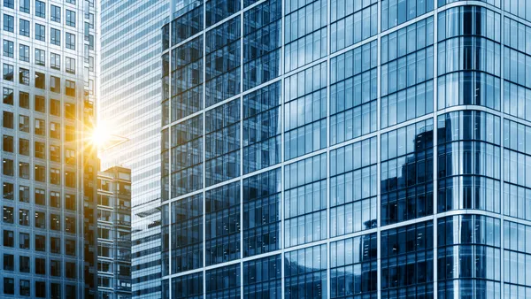 A view of a contemporary glass skyscraper reflecting the blue sky.