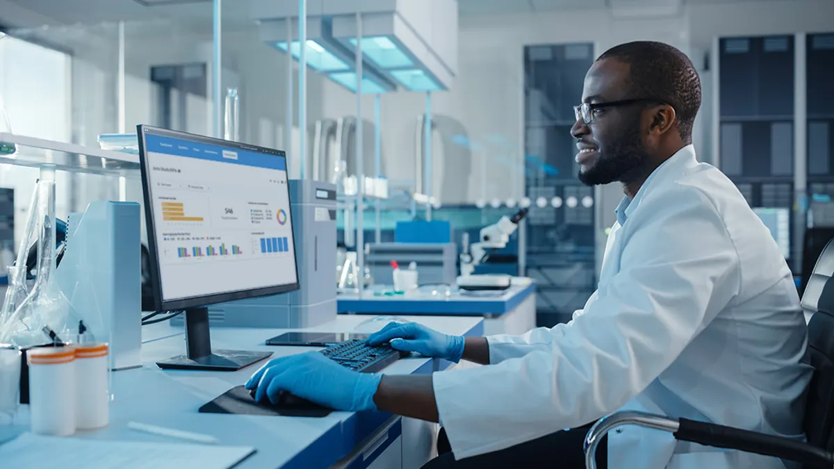 Male in lab coat looking at monitor screen