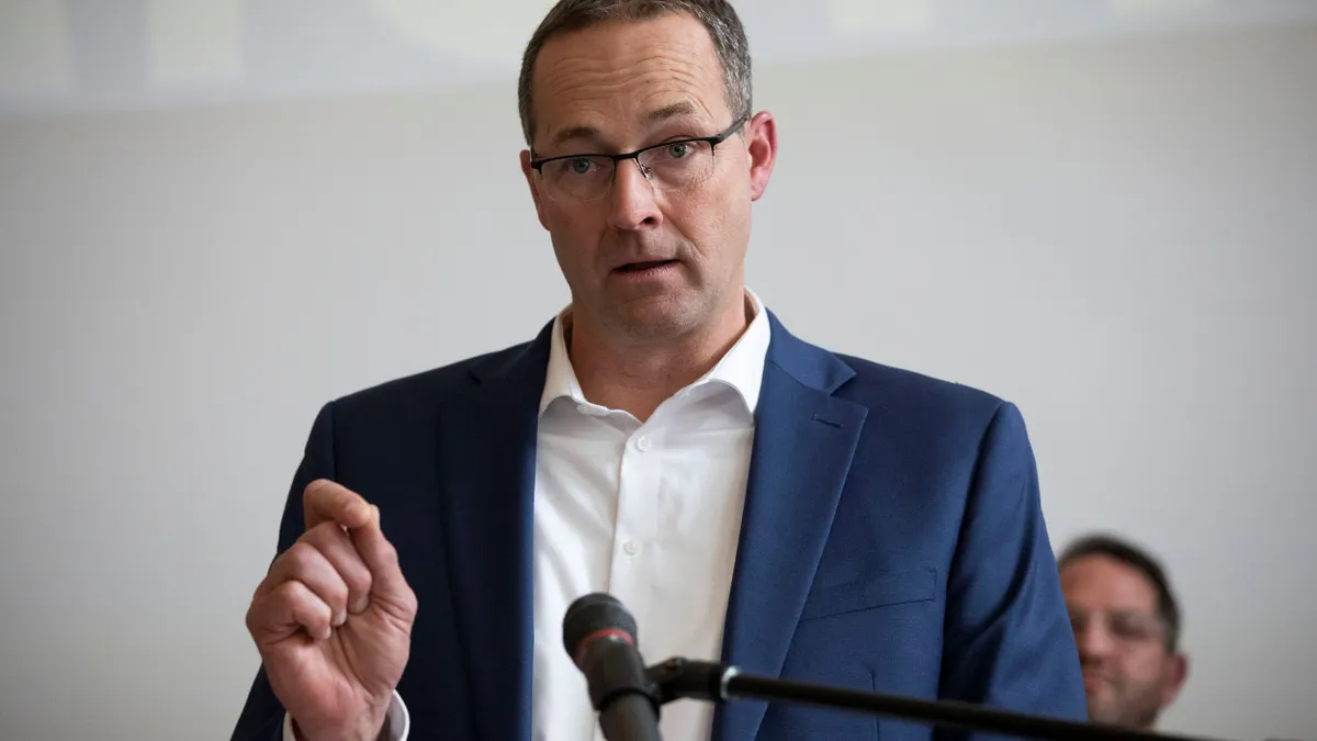 A person in a suit gesturing while speaking.