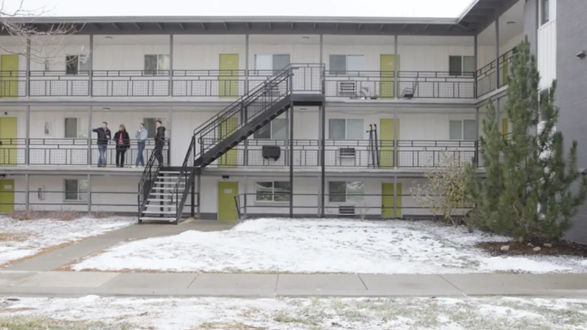 Three-level apartment building with railing and steps and people on the second floor.