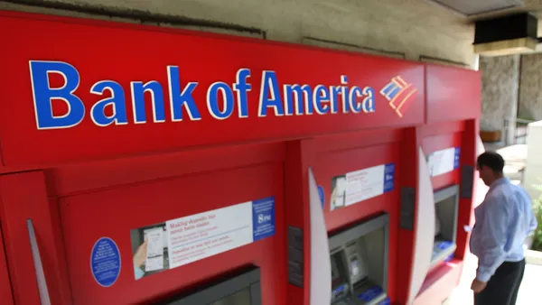 A person uses a red Bank of America ATM.