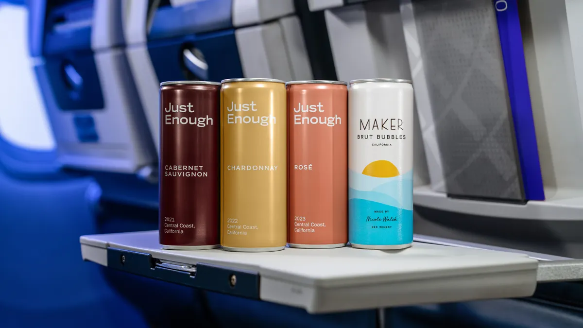 Four different colored cans of wine on an in-flight tray table.