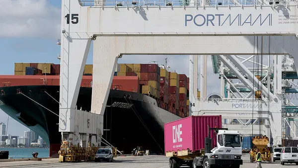 A vessel is docked at PortMiami and containers are being moved using gantry cranes.