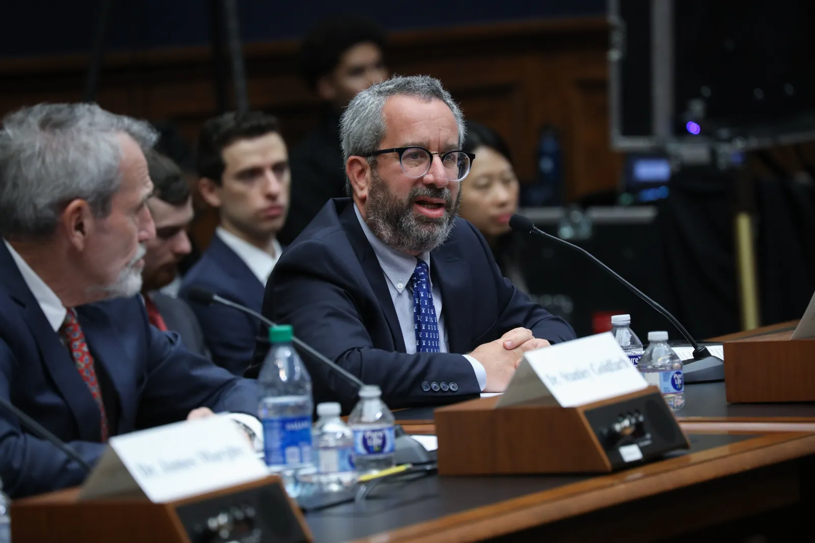 A person is sitting at a desk behind a microphone