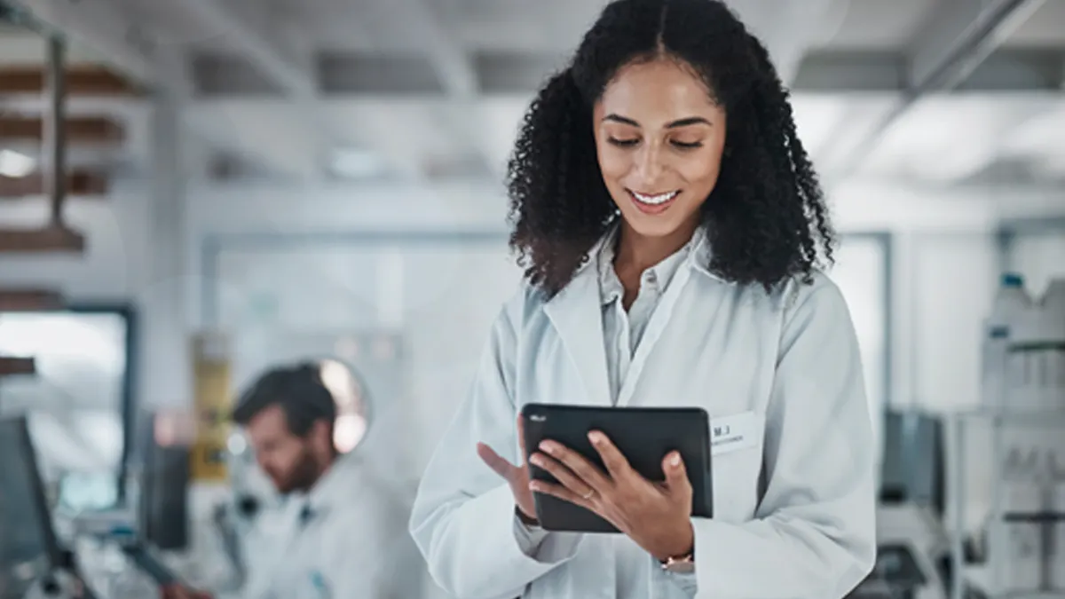 Woman wearing labcoat while using tablet