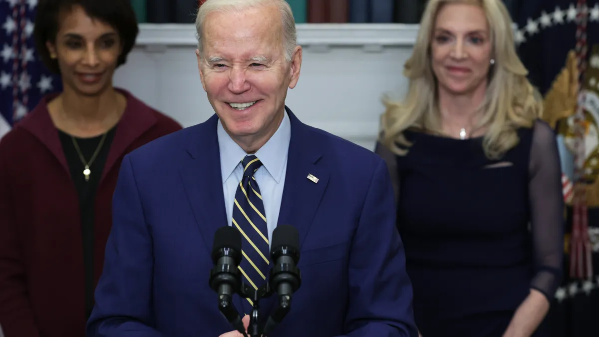 A man in a suit speaks at a podium.