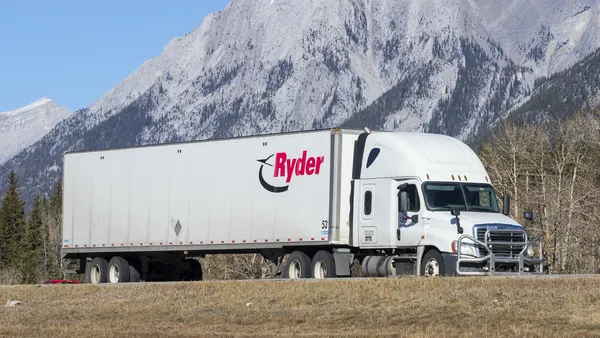 A Ryder tractor-trailer shown with mountains in the background on the Trans-Canada Highway in Canmore, Alberta.