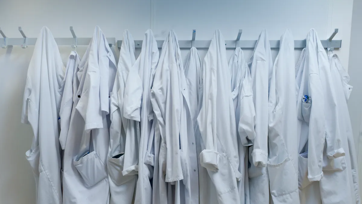 White lab coats hanging from hook at laboratory