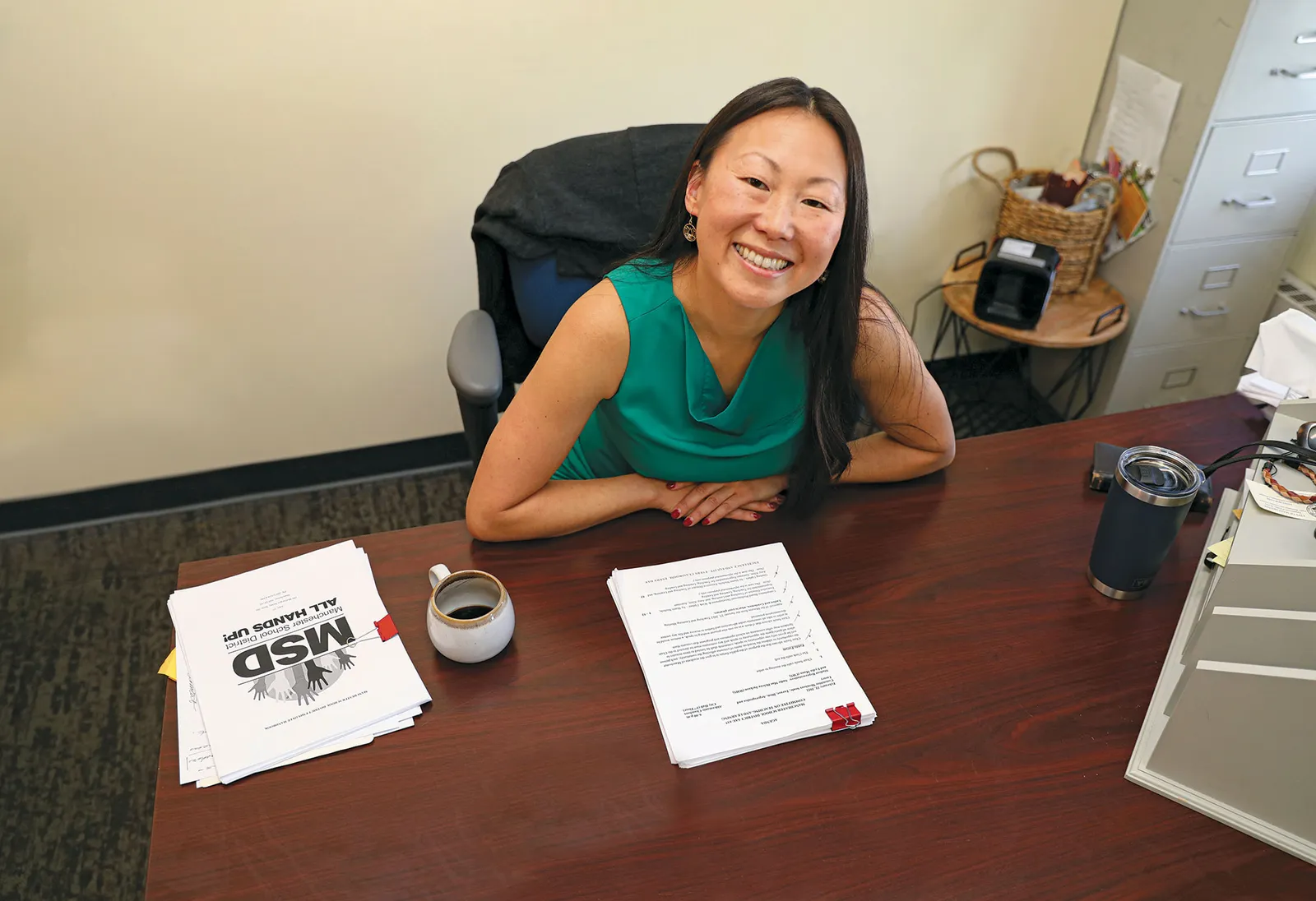 A person smiles for a portrait at a desk.