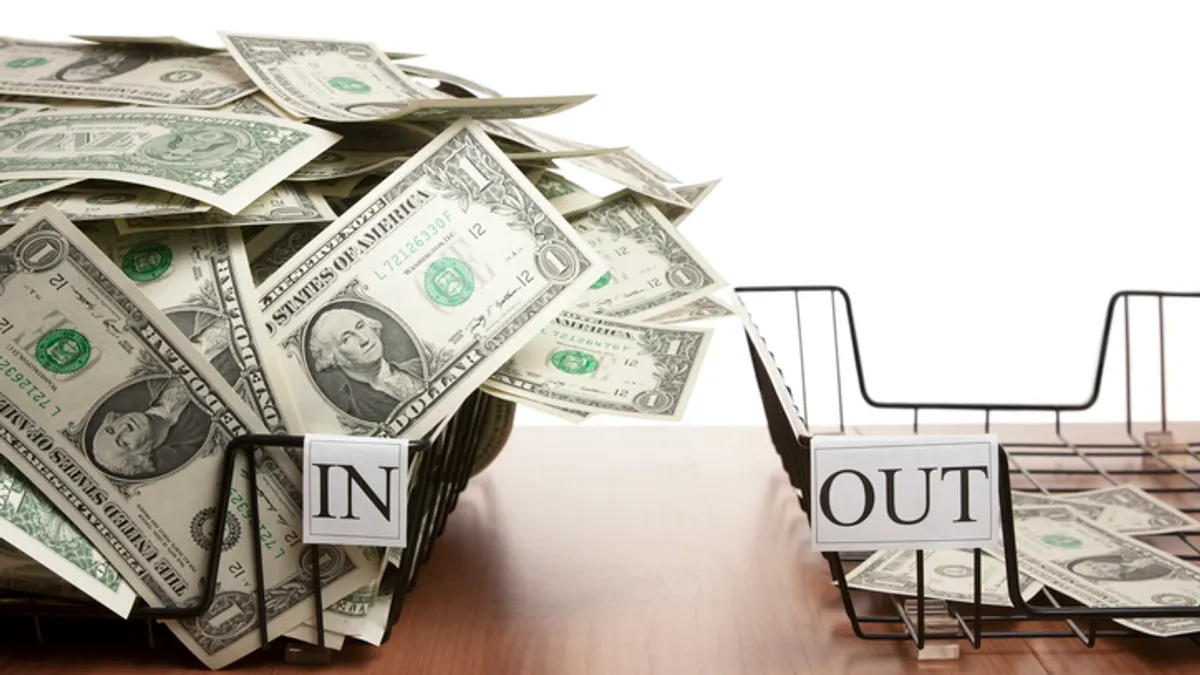 In tray overflowing with dollar notes and empty out tray