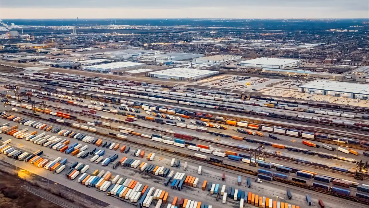 An aerial view shows a rail freight station with shipping containers and warehouses in Chicagoland.