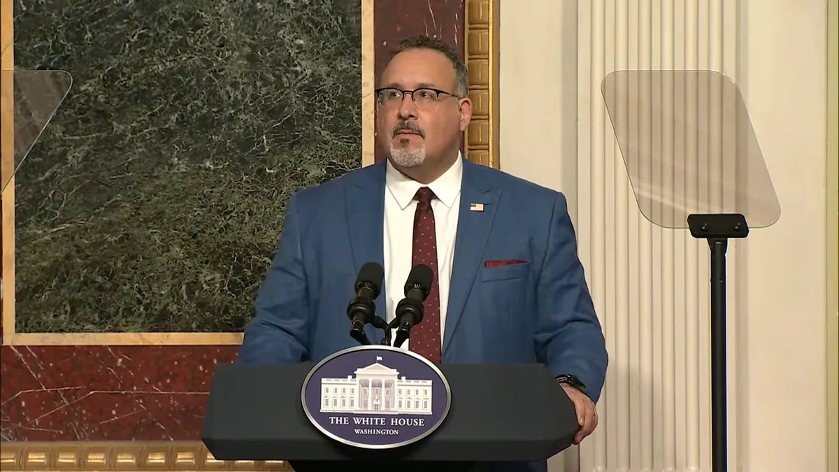 U.S. Secretary of Education Miguel Cardona speaks at a podium