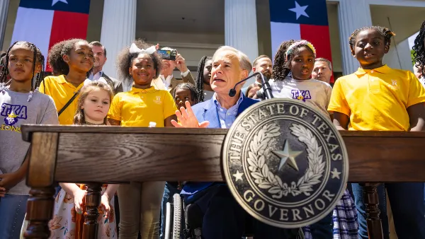 Gov. Greg Abbott speaks from a podium surrounded by students