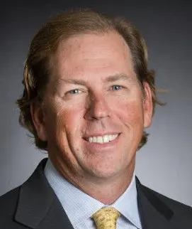 Man smiling in a dark jacket.