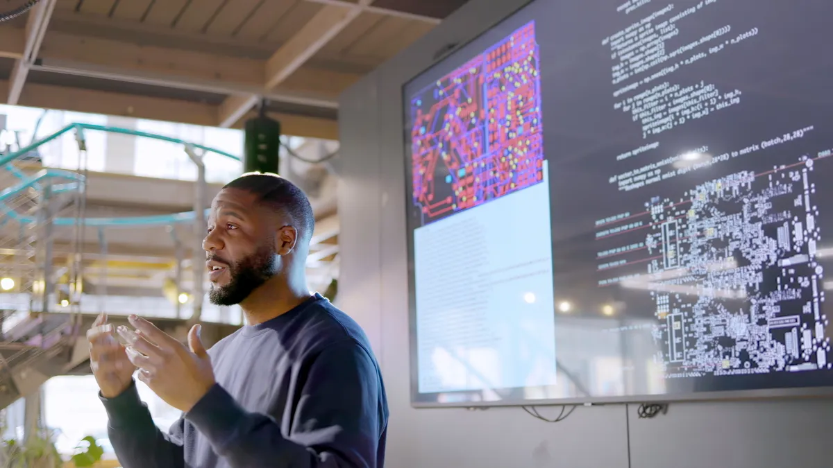 Man infront of tv screen giving a presentation