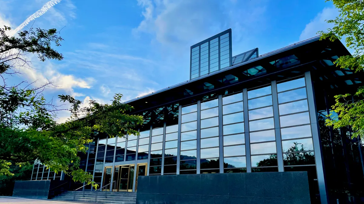 A building with lots of glass windows under a blue sky.