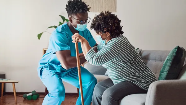 Shot of a young male nurse helping an elderly patient stand.