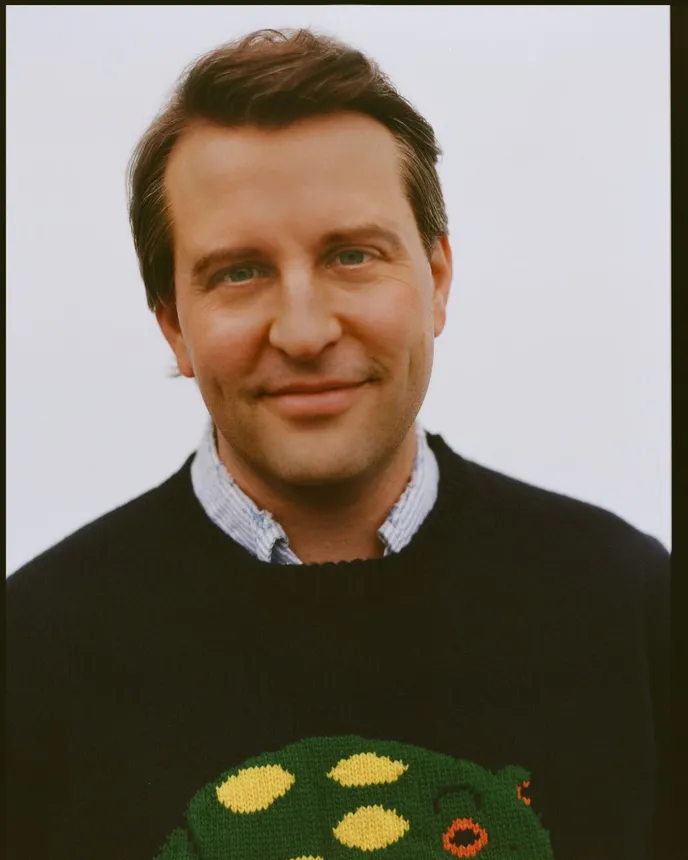 A headshot of Jack Carlson, founder of Rowing Blazers. He is wearing a sweater with a frog on it.