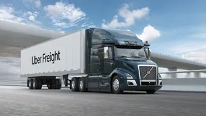 A freight truck on the roads under a highway bridge.