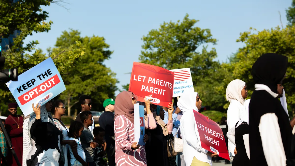 Protestors wearing religious garb hold signs that read "Let Parents Parent"