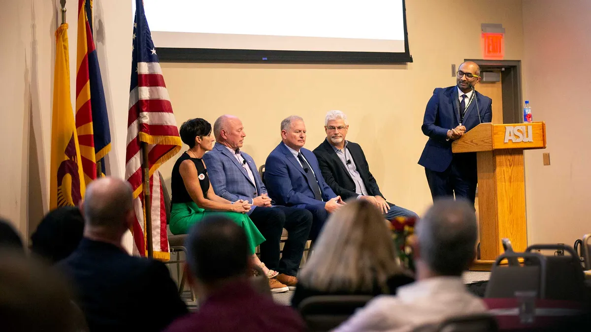 A panel of industry leaders sit on stage.