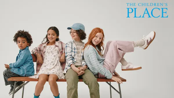 Children sitting on a bench in front of the logo for The Children's Place.