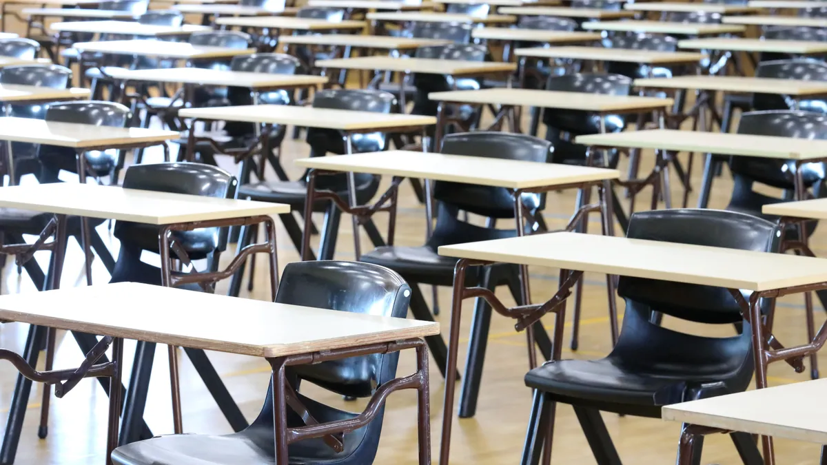 Rows of empty desks and blue chairs fill a high school classroom