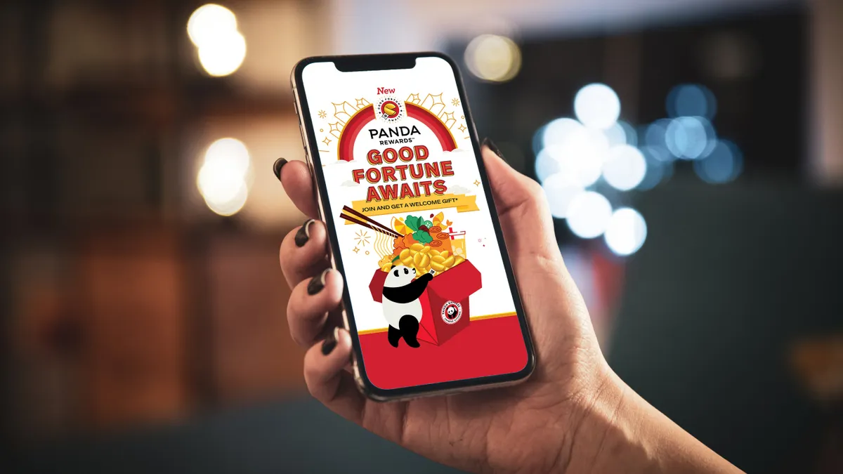 A hand holding a phone with an image promoting Panda Express' new rewards program.