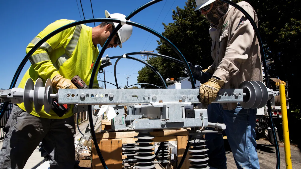A utility crew installs a new overhead switch.