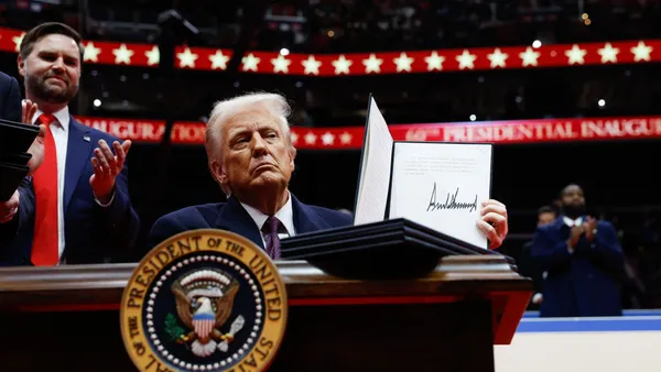 President Donald Trump holds up an executive order after signing it at Capital One Arena in Washington, D.C.