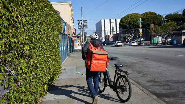 A DoorDash delivery worker walks his bike along the road in the Mission neighborhood of San Francisco, California.