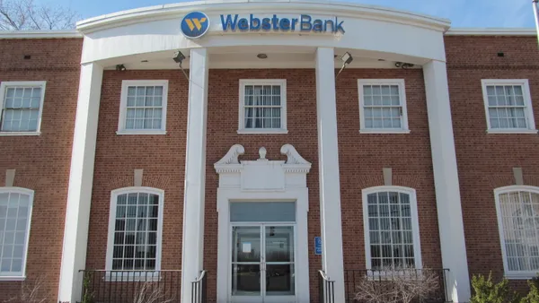 The front of a two-story brick bank building with the company name and logo.