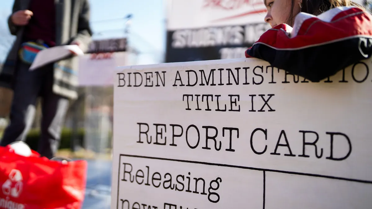 A student protesting Title IX holds a sign