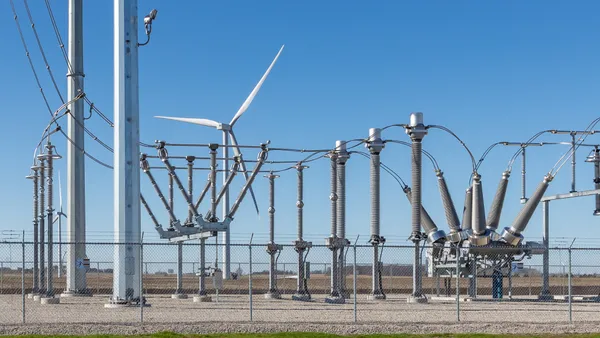 electrical substation with a wind turbine in background supplying the power