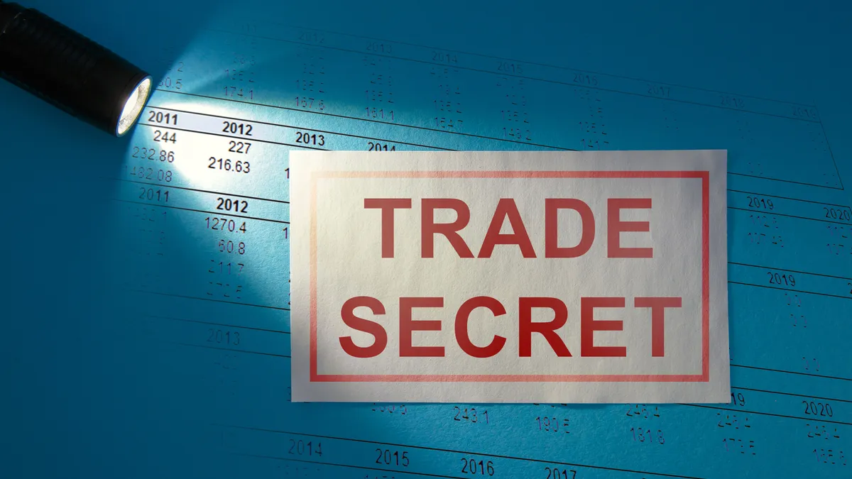 An inscription that says "trade secret" on a white card under a beam of light