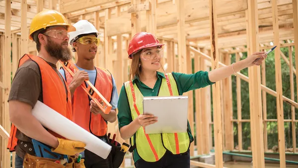 Three people wearing protective construction gear on a construction worksite.