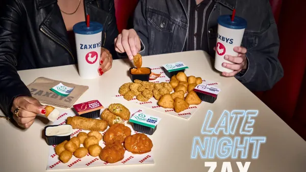 Two people hold Zaxbys food.