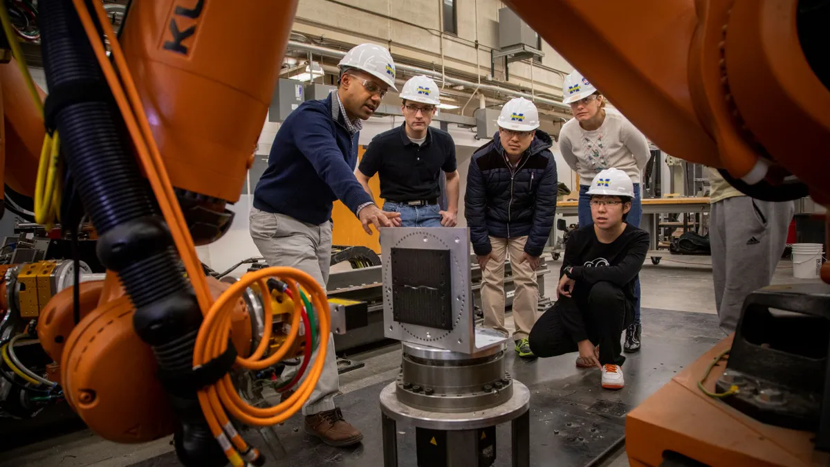 Engineers and scientists gather around machinery.