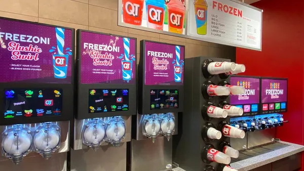 A photo of a bank of frozen drink dispensers. The signs on the machines say Freezoni Slushie Swirl, while a menu above the machines says Frozen.