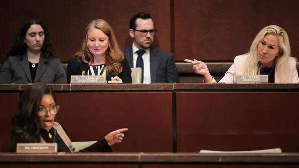 Lawmakers sit in a DOGE subcommittee hearing with pictures of a witness displayed